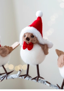 Close-up of plush Christmas bird ornament with red Santa hat on white snowy branch