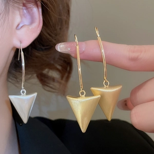 Close-up of geometric brushed metal triangle drop earrings in gold and silver finish