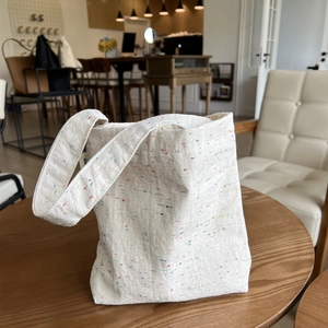 Chic beige canvas tote bag with colorful speckled pattern on wooden table