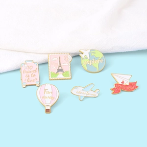 Travel-themed enamel pin set with hot air balloon and luggage on light blue background