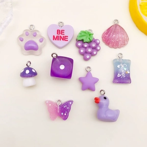 Flat lay of purple resin charms including cat paw, grape and heart for DIY jewelry