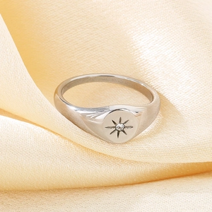 Macro shot of silver signet ring with engraved starburst and inset cubic zirconia detail