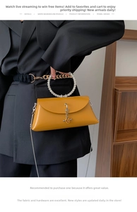 Detail of ginger yellow crossbody bag with crystal handle and metal chain on black suit