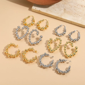 Flat lay of multiple gold and silver beaded hoop earrings on minimalist beige background