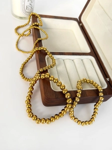 Dettaglio macro del bracciale a sfere in acciaio inossidabile dorato 18K su scatola in legno