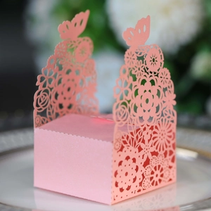 Macro detail of laser-cut pink butterfly candy box with floral patterns on a porcelain plate