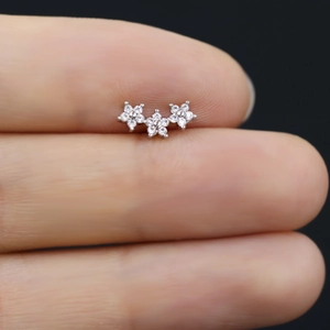 Dettaglio ravvicinato di piccoli orecchini a lobo a triplo fiore in argento con zirconi