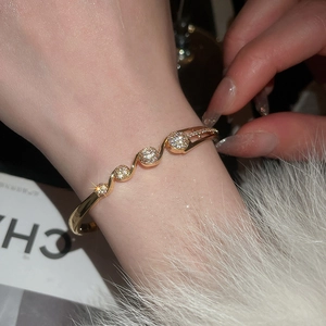 Détail d'un bracelet doré ondulé avec zircons porté au poignet d'un mannequin