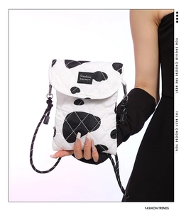 Detail of cow print quilted crossbody bag with woven strap and fashion patch