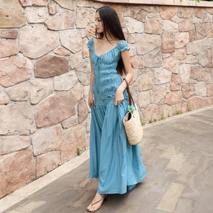 Détail de la robe bleue à col en V avec texture plissée élégante et style épaules dénudées