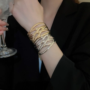 Detail of layered gold interwoven cuff bracelet worn by model in formal setting
