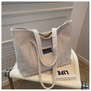 Detailed texture of off-white canvas tote bag placed on a minimalist chair