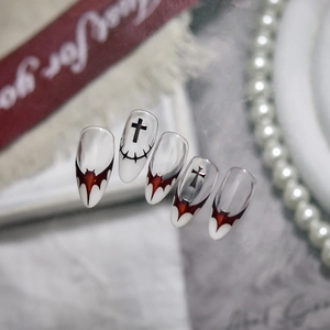 Macro shot of gothic nail art featuring bat wings and crosses with silk ribbon