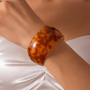 Close-up of wide chunky acrylic bracelet with amber tortoise shell pattern on model wrist