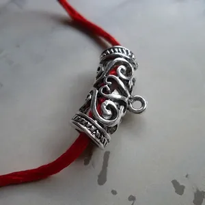 Macro view of vintage silver hollow curved bead with floral engraving and red cord