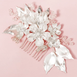 Detailed view of silver bridal hair comb with crystal flowers and leaves on pink background