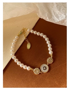 Détail d'un bracelet perlé plaqué or 18k avec perles lustrées et breloques zircon