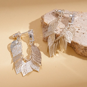 Gros plan de boucles d'oreilles à pampilles feuilles évidées sur socle en pierre