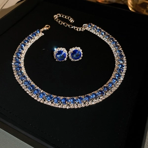 Detailed view of gold jewelry set with blue gemstones and sparkling cubic zirconia stones