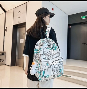 Graffiti print backpack in white with green and black patterns shown on a female model