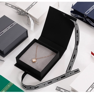 Top view of jewelry gift boxes in multiple colors with silk ribbons and clover necklace