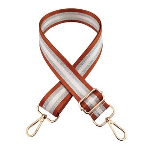 Detail of adjustable orange and white striped handbag strap with golden metal clips