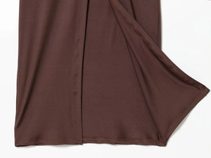 Detail view of dark brown knitted dress hem featuring a side slit and refined stitching