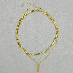 Detail view of double-layer gold stainless steel Cuban chain with rectangular bar pendant