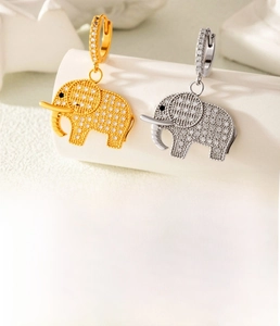 Vue macro de boucles d'oreilles éléphant en cuivre serties de zircon en doré et argenté