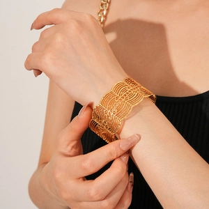Nahaufnahme eines breiten goldenen Armreifs mit komplexen geometrischen Cut-Out-Mustern