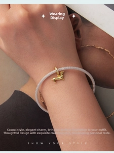 Lifestyle shot of gold-plated dachshund charm on silver mesh bracelet jewelry piece