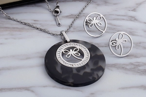 Detailed macro view of silver stainless steel dragonfly necklace and earrings set