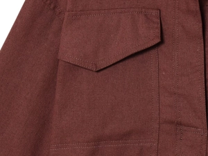 Detailed macro view of the dark red cotton linen fabric and pocket stitching on this suit