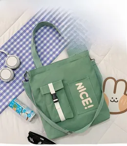 Detail of green canvas tote bag featuring a buckle pocket and adjustable shoulder strap