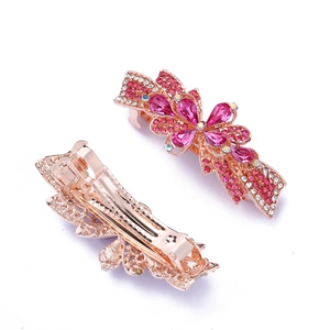 Pink crystal flower bow hair clip with gold metal spring clamp on white background