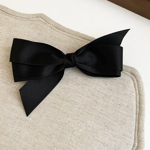 Détail d'un nœud en satin noir élégant avec texture lisse sur fond de lin beige