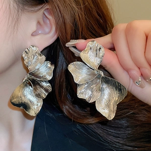 Vintage silver metal flower petal stud earrings with layered heavy duty texture on model