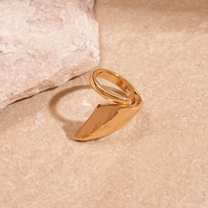 Detailed close-up of golden irregular geometric open ring on natural stone texture