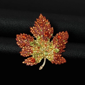 Close-up of maple leaf brooch with colorful rhinestones on black leather background