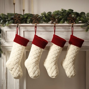 Close-up of four cable-knit Christmas stockings hanging on a festive decorated white fireplace