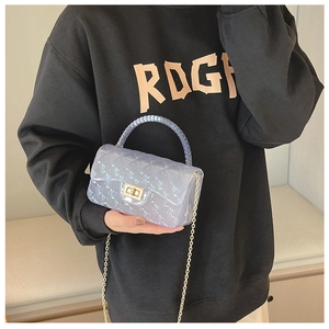 Detail of transparent blue jelly crossbody bag with quilted texture and gold chain strap