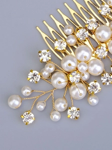 Close-up of handmade bridal hair comb with gold metal, white pearls and clear rhinestones