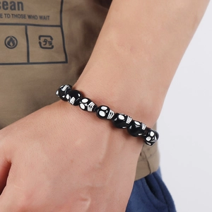 Close-up of model wearing black skull bead elastic bracelet with gothic retro details