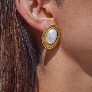 Macro close-up of a vintage golden pearl earring worn by a model to show elegant details