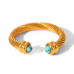 Detail of golden spiral twist cable cuff bracelet with turquoise stone insets