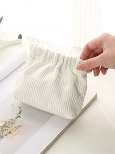 Detailed view of hand-held soft white corduroy pouch with a drawstring closure design