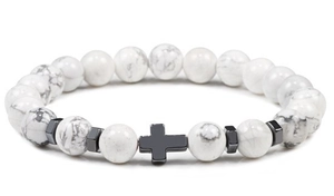 Macro shot of white marble beads and a black metal cross charm on an elastic bracelet