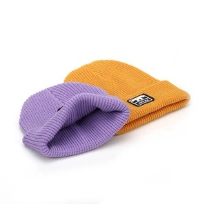 Detail of ribbed knit beanies in purple and ginger yellow with animal patch
