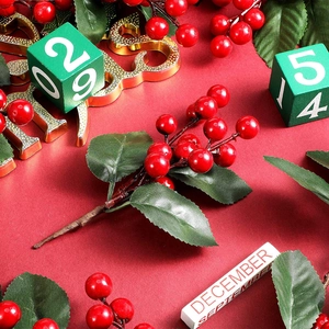 Mini albero di Natale artificiale con bacche rosse e foglie verdi su sfondo rosso