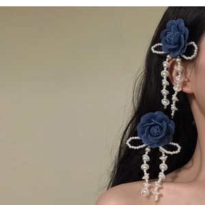 Dettaglio di rose in denim blu con eleganti nappe di perle bianche e fermaglio a fiocco